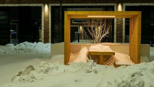 Benches and tables are covered with snow after a winter storm in the courtyard of a house in Moscow. evening shooting. color