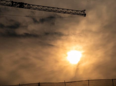silhouette of a construction crane behind a sunset