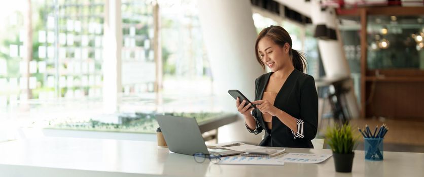 Business asian woman using mobile phone during checking an email or social media on internet. accounting financial concept