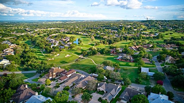 A bird's-eye view of the surroundings of residential buildings and beautiful green fields. Houston, Texas, USA. Development of suburban housing construction