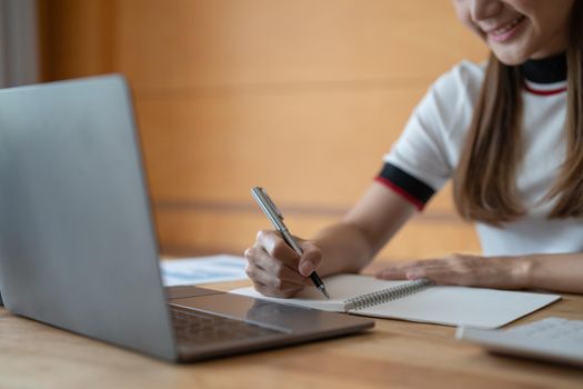 Young asian woman writing notes in notebook watching webinar video course, serious black male student looking at laptop listening lecture study online on computer e learning.