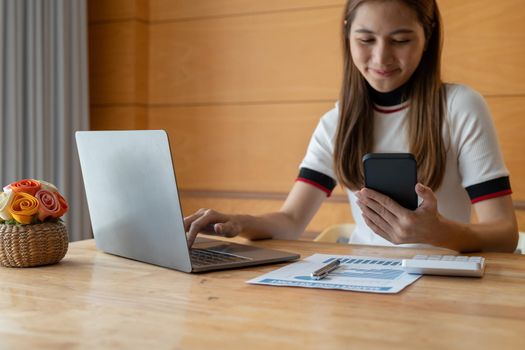 Asian woman hand using smartphone calculate for analysis and budget financial accounting with growth statistics chart and graph on paperwork. accounting financial concept.