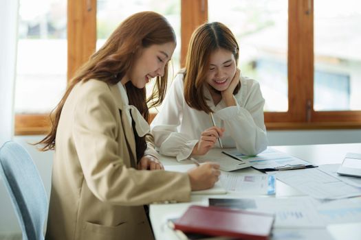 Two asian business woman and partner using calculator and laptop for calaulating finance, tax, accounting, statistics and analytic research concept.