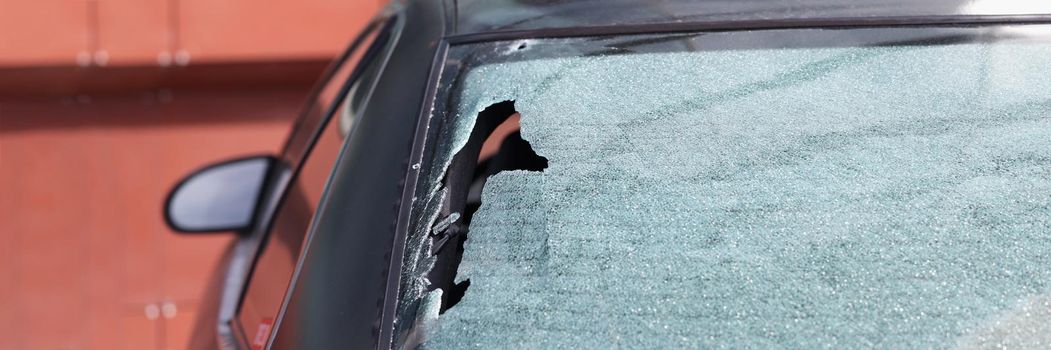 Close-up of car window broken by accident with stone or smashed by thief, hacking auto. Criminal incident, car insurance, vehicle, night crime, vandalism concept