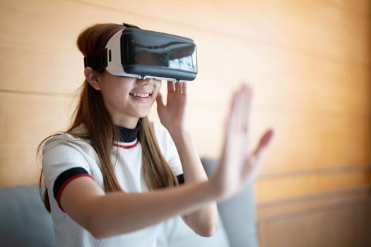 Excite asian woman playing online game with vr glasses and controller at her home.