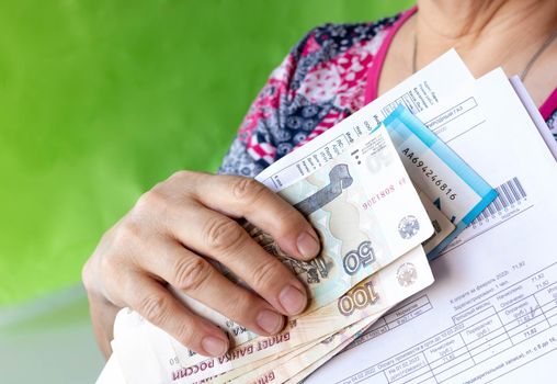 The hand holds Russian banknotes and receipts.