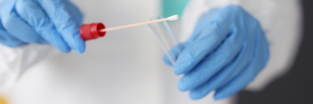 Close-up of doctor in protective suit medical mask gloves holding swab saliva sample for diagnostic, coronavirus virus in lab. Coronavirus, testing, medicine, healthcare concept