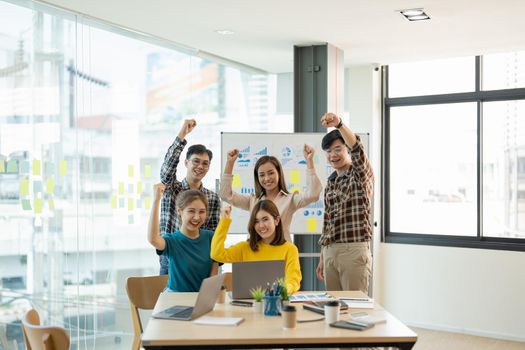 Group of young business team startup celebrating a triumph with arms up, Diverse business people happy success in boardroom