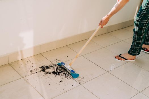 Man wiping floor with the mop. Janitor washing the dirty floors. Guy mopping the balcony on a sunny day. Person doing home chores. Young fellow using cleaning equipment to dust the surface.