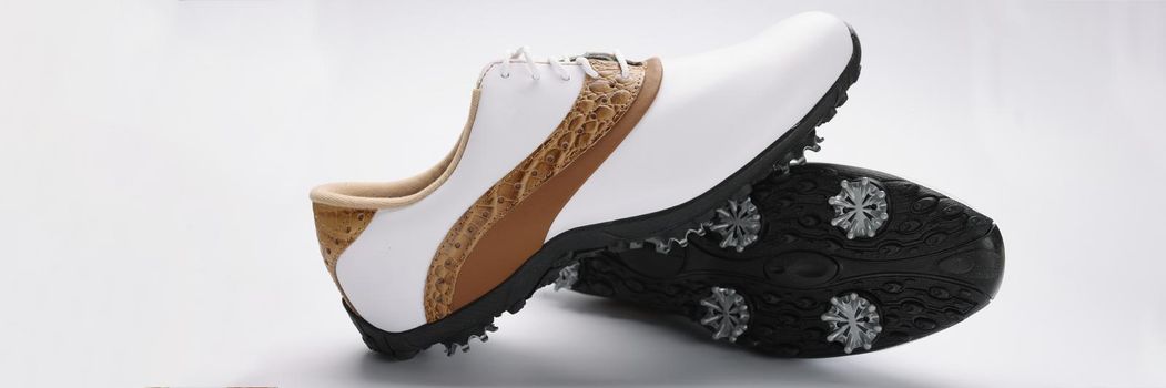 Close-up of pair of modern fashionable shoes with unique design, white with combination of gold colours, metal things on sole. Footwear, fashion industry, design concept