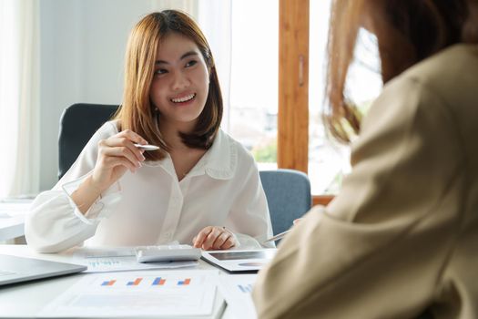 Two young beautiful asian business woman in the conversation, exchanging ideas at modern office