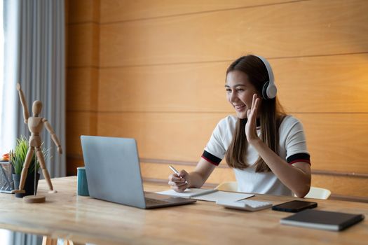 Smiling girl student wear taking note for study online with teacher, happy young woman learn language listen lecture watch webinar write notes look at laptop at home, distant education.