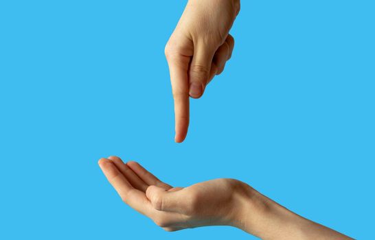 Close-up of women's hands, side view with the palm up, and the second hand points a finger at the palm. isolated on a blue background.
