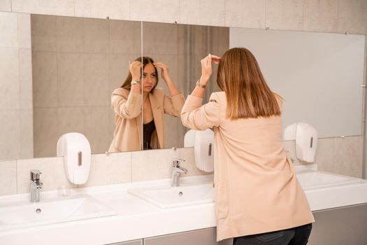 A woman washes her hands under running tap water in a public toilet