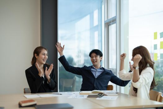 Euphoric excited young asian business team celebrate corporate victory together in office