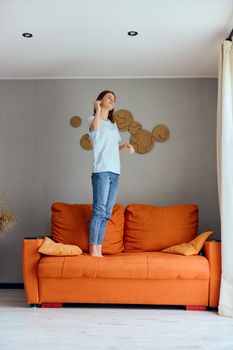 pretty woman in jeans is standing on the couch fun. High quality photo