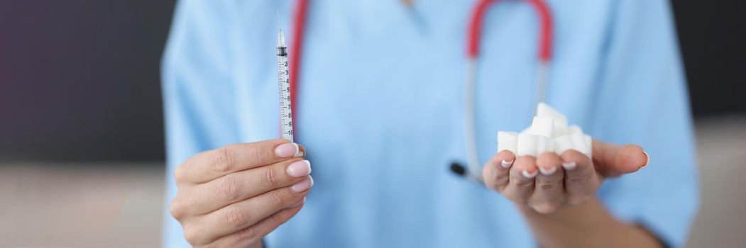 Close-up of doctor hands holding dose of insulin in syringe and loaf-sugar in hands. Medicine and treatment for diabetes. Diabetes Day, support and care concept