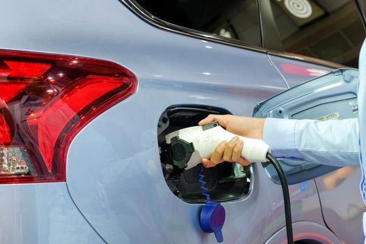 Close-up Asian women hands who are fueling a new vehicle electrification via rechargeable electricity machine, Electric cars are a new innovation in the future, built to replace cars powered by oil