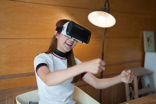 Excited young woman in VR goggles driving car in virtual reality. Lady screaming when turning virtual steering wheel, teen playing in racing computer game or road simulator, enjoying 3d gaming at home