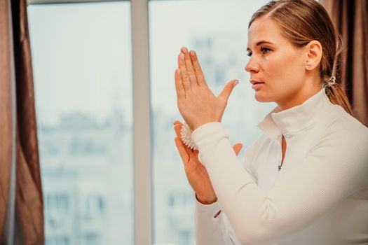 Athletic slim caucasian woman doing thigh self-massage with a massage ball indoors. Self-isolating massage.