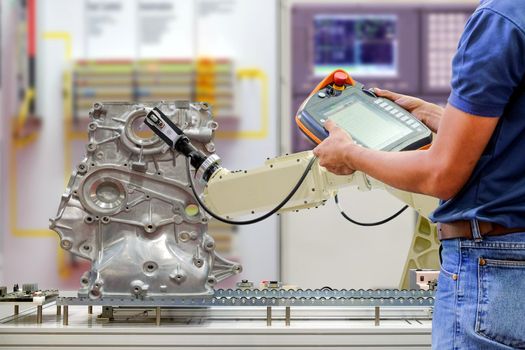 Engineers use a wireless remote for control robotic for work scanning part of automobile via conveyor belt on smart factory on blurred control panel background, industrial 4.0