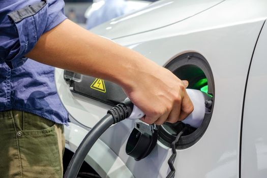 Close-up Asian men hands who are fueling a new vehicle electrification via rechargeable electricity machine, Electric cars are a new innovation in the future, built to replace cars powered by oil