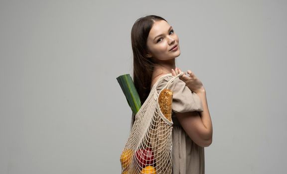 Young woman holding reusable cotton shopping mesh bag with groceries from a market. Concept of no plastic. Zero waste, plastic free. Eco friendly concept. Sustainable lifestyle