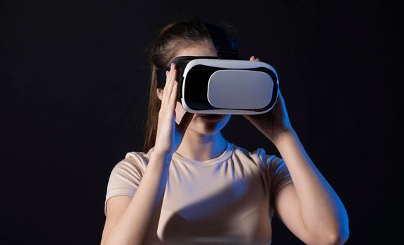 Woman architector using virtual reality glasses at workplace and working with a new project. Woman working in VR goggles in neon light. Designer working in VR studio