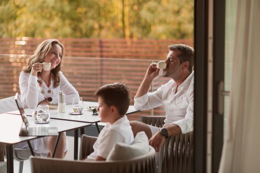 An elderly couple enjoys the terrace of a luxury house with their son during the holidays. Selective focus. High-quality photo