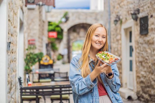 Young woman tourist eating traditional pizza in the old town of Budva. Travel to Montenegro concept.