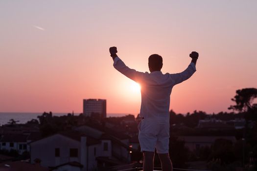 an elderly businessman in casual clothes enjoys the roof of his house at sunset time. Selective focus. High-quality photo