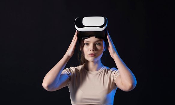 Brunette woman gamer with a virtual reality glasses ready to play a game or explore the environment in a metaverse world. Modern technologies