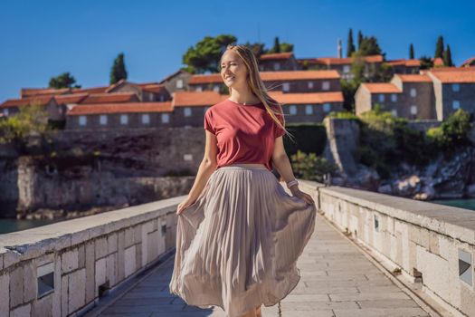 Woman tourist on background of beautiful view of the island of St. Stephen, Sveti Stefan on the Budva Riviera, Budva, Montenegro. Travel to Montenegro concept.