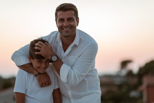 Father and son spend time together on the roof of the house while enjoying the sunset. Selective focus. High-quality photo