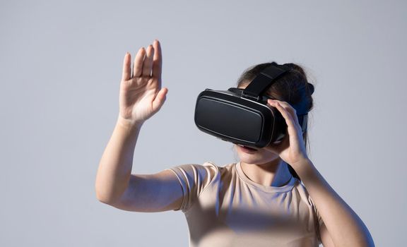 Close up of young woman stands in studio wearing VR glasses and swiping scrolling with hands in air. Virtual reality technology