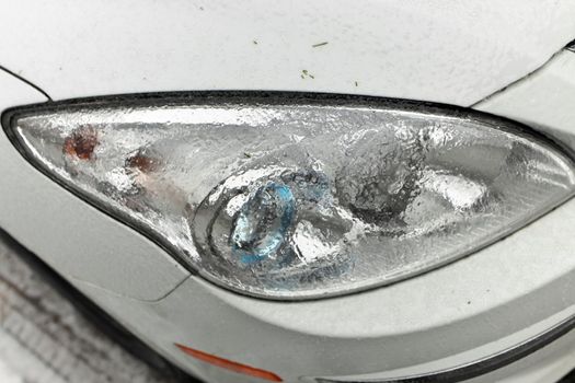 Freezing Rain Creates a Layer of Ice and Coats a Passenger Vehicle. Close up of Headlights. High quality photo
