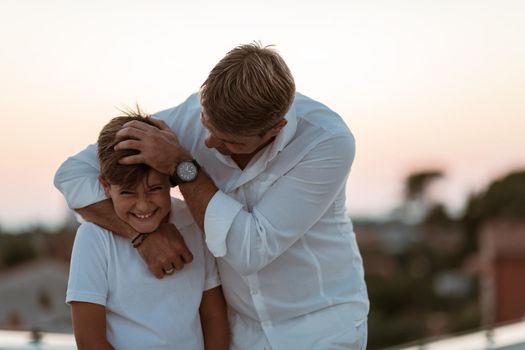 Father and son spend time together on the roof of the house while enjoying the sunset. Selective focus. High-quality photo