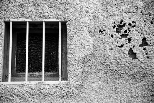 Old chipped house facade with little window. Monochrome picture.