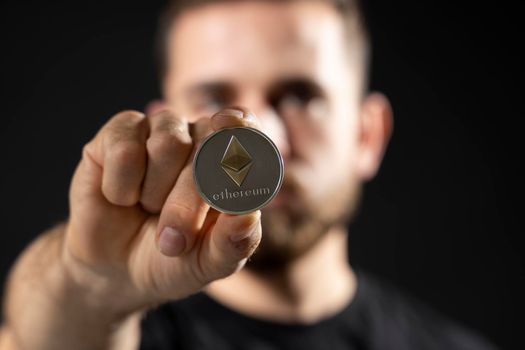 Young bearded man holding virtual currency ethereum coin and bitcoin. Cryptocurrency