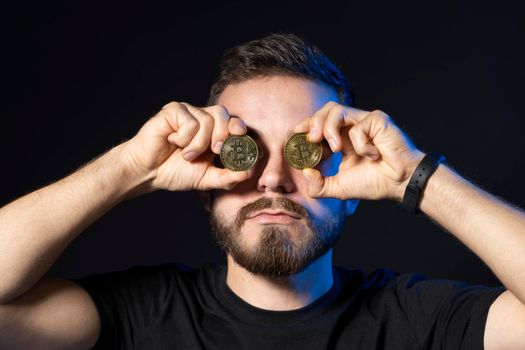 Bitcoin lover with golden coin by eyes. Digital symbol of a new virtual currency. Cryptocurency