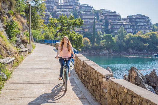 Woman tourist on a bicycle explores Budva in Montenegro. Cycling in Montenegro concept.