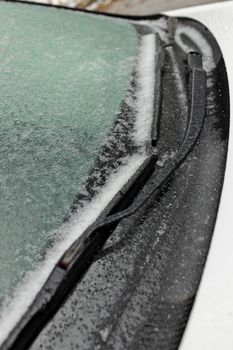 Freezing Rain Creates a Layer of Ice and Coats a Passenger Vehicle. Close up of Windshield and Wiper Blades. High quality photo