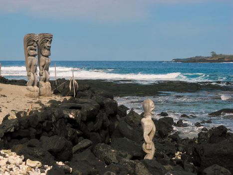 Wooden carvings resembling Hawaiian gods, Kii, stand along the ocean shore at Puuhonua o Honaunau National Historical Park. High quality photo