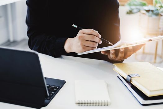 An accountant, businessman, auditor, economist man holding a pen pointing to a budget document and using tablet to examine and assess financial and investment risks for a company