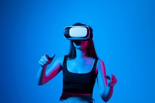 Young girl playing game using VR glasses, enjoying virtual reality headset while gaming with a friends in metaverse in neon light