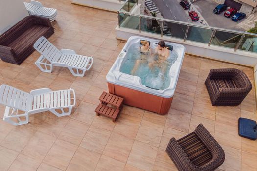 Drone view. Portrait of young carefree happy smilingcouple relaxing at hot tub during enjoying happy traveling moment vacation life against the background of green big mountains.