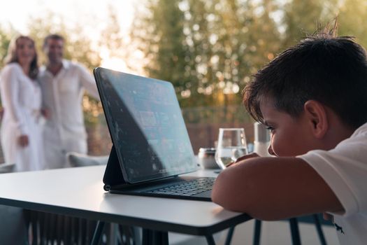 Happy elderly couple resting on the balcony of a luxury house while their son using a tablet. Selective focus. High-quality photo