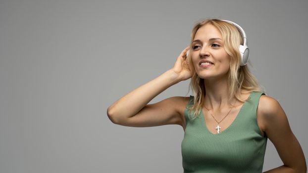 Beautiful blonde girl in green t-shirt in headphones having fun in studio dancing and laughing