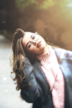 young beautiful girl posing on the street. Dressed in a stylish gray coat and knitted pink sweater.