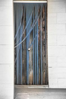 Wooden door with blue striped plastic curtain in Spain